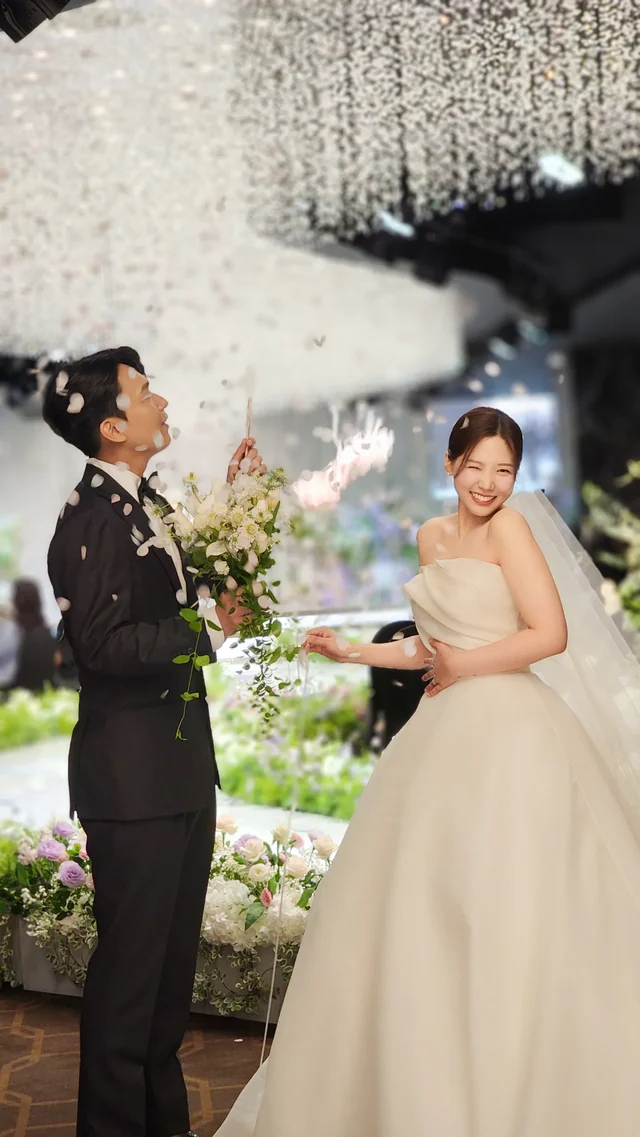 꽃가루가 흩날리는 통로를 함께 걸어 나오는 신랑신부