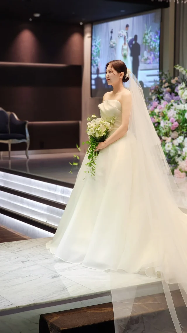 예식홀 단상에 홀로 선 신부의 드레스 전신