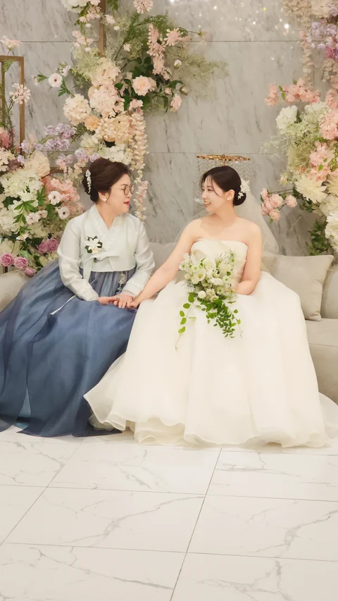 푸른 한복을 입은 어머님과 손을 맞잡고 앉은 신부