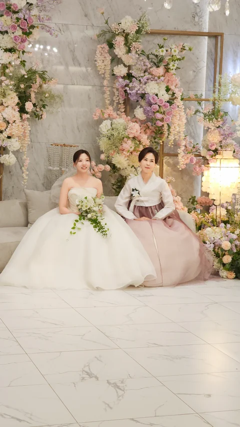 분홍 한복 차림 어머님과 손을 맞잡고 앉은 신부