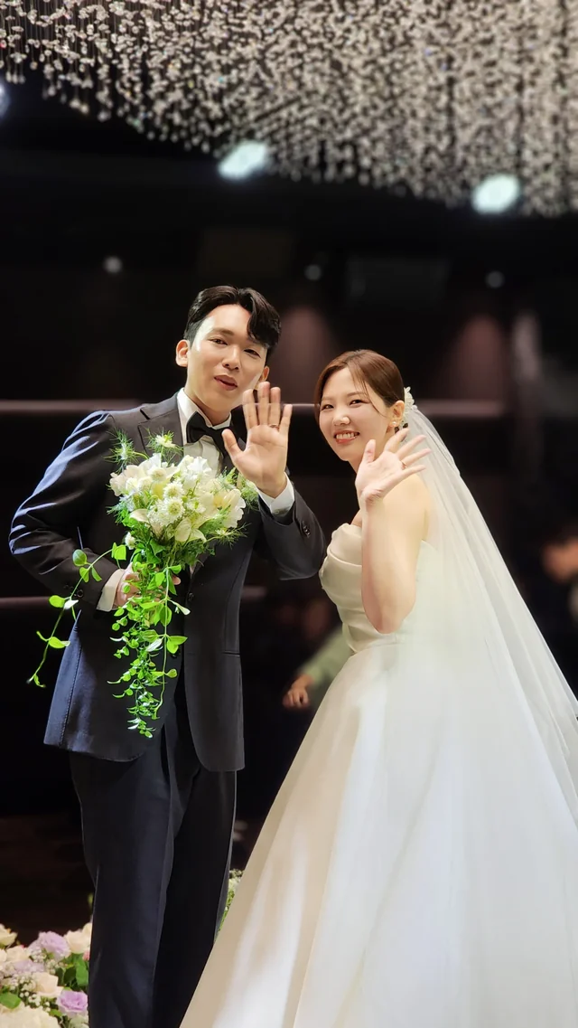 부케를 든 채 하객에게 손을 흔드는 신랑신부