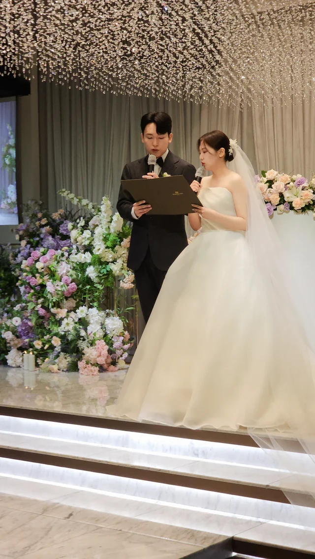 단상에서 혼인 서약서를 펼쳐 읽는 신랑과 곁에 선 신부